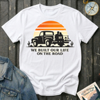 We Built Our Life on the Road T-shirt by The Riverstone Life on a white Gildan Softstyle 64000 featuring a vintage pickup truck, couple, retro sunset inspired by RV life and adventure.