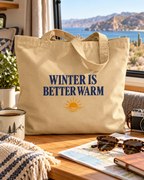 Winter is Better Warm tote with a sun sitting on a table inside an RV with a water scene outside