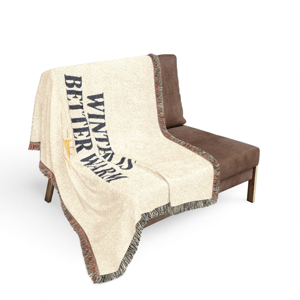 Beige blanket with a bird design and text draped over a brown chair on a white background